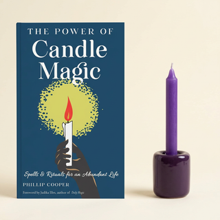 The Power of Candle Magic book beside a purple spell candle in a purple ceramic holder; other colors available