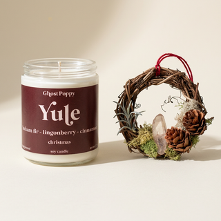 Yule candle beside a miniature crystal moss wreath ornament